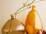 beautiful amber irregular bottles with some blooming branches are a refined decoration for a modern space