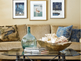 a seaside living room with an inspiring gallery wall, a bowl with seashells and a blue glass bottle on the table